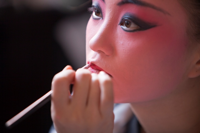 A Chinese opera singer putting on makeup.